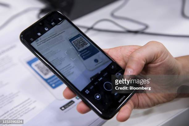 Visitor uses CovPass, Germany's new vaccination passport smartphone app, to scan a QR code after being inoculated at a Covid-19 vaccination center in...