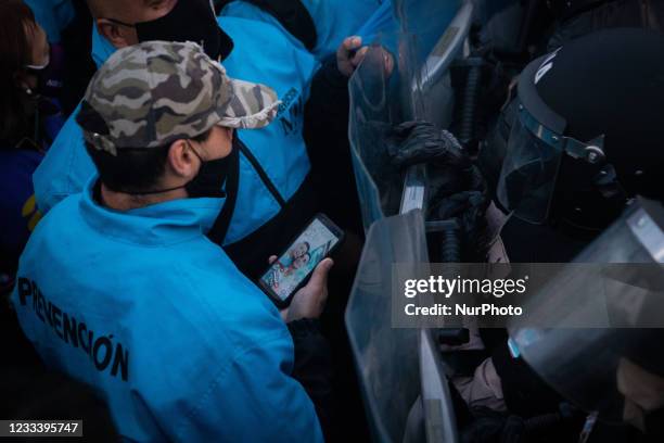 Man holding his cell phone stands in front of riot police during a protest held by people who were fired during the covid-19 pandemic in Buenos...