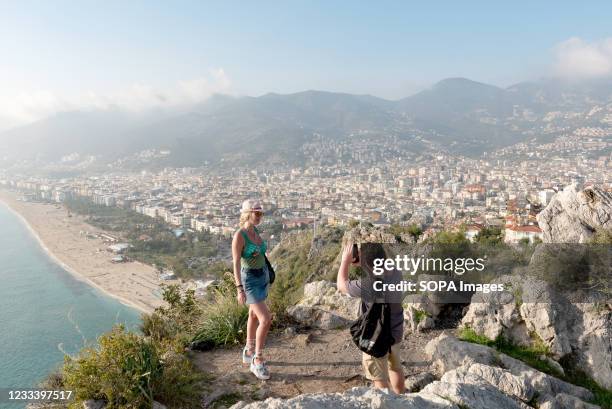 Tourist posing for photographs on the mountain overlooking the city of Alanya and Kleopatra beach on the Mediterranean coast of Turkey. The Turkish...