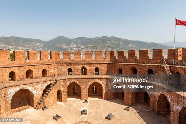 The imposing battlements of the Seljuk era Red Tower or Kizil Kule overlooking Alanya harbour with the Taurus Mountains in the background. The...
