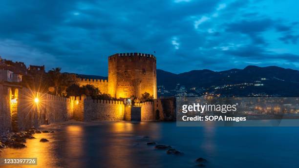 Stunning panorama of Alanya Harbour and the Red Tower at night with the Taurus Mountains and Mediterranean Sea. The Turkish seaside resort of Alanya,...