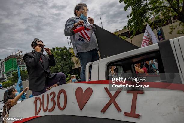 Filipinos wearing masks depicting Philippine President Rodrigo Duterte and China's President Xi Jinping as they mark Independence day with a protest...