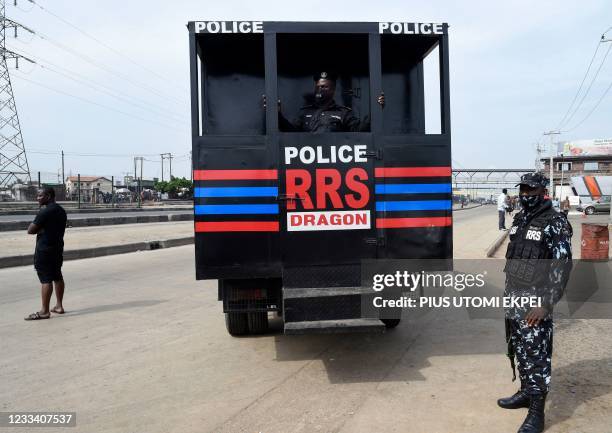 Anti-riots policemen wait for detained protesters to transport them in a police truck during a demonstration at Ojota in Lagos on June 12 as Nigerian...