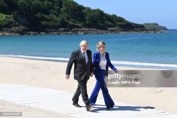 Britain's Prime Minister Boris Johnson and his spouse Carrie Johnson walk along the boardwalk during an official welcome at the G7 summit in Carbis...