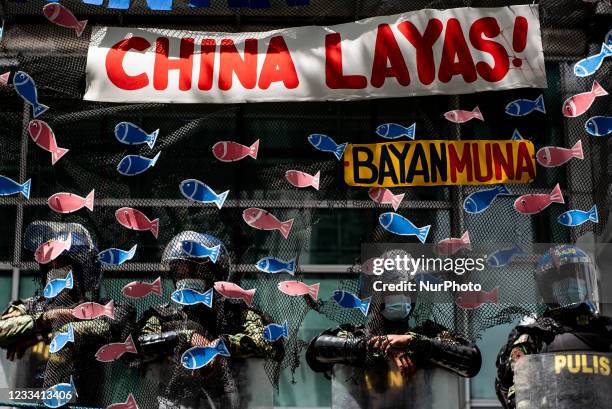 Police officers guarding the Chinese Consulate are pictured behind a fishing net during a protest in commemoration of 123rd Philippine Independence...