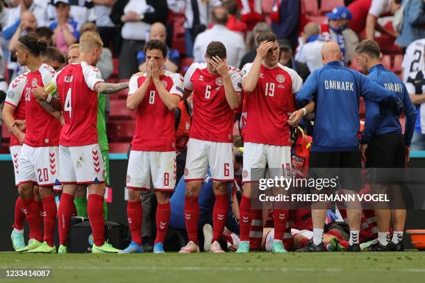 Players gather as paramedics attend to Denmark's midfielder Christian Eriksen during the UEFA EURO 2020 Group B football match between Denmark and...