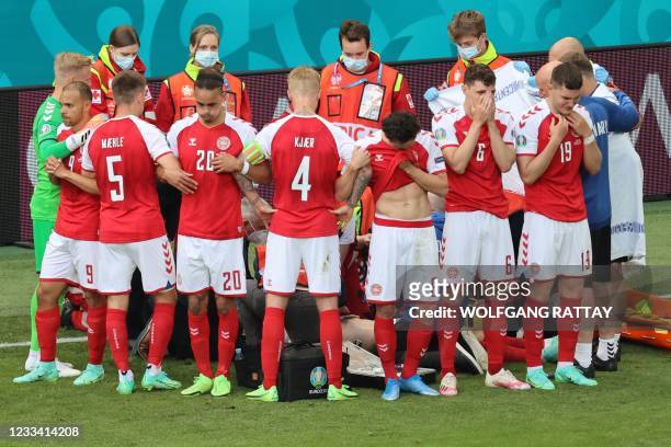 Denmark's players gather as paramedics attend to midfielder Christian Eriksen during the UEFA EURO 2020 Group B football match between Denmark and...