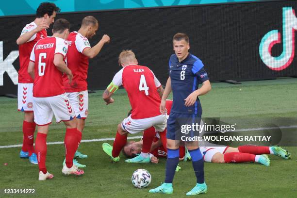 Players gather as Denmark's midfielder Christian Eriksen lies on the pitch during the UEFA EURO 2020 Group B football match between Denmark and...