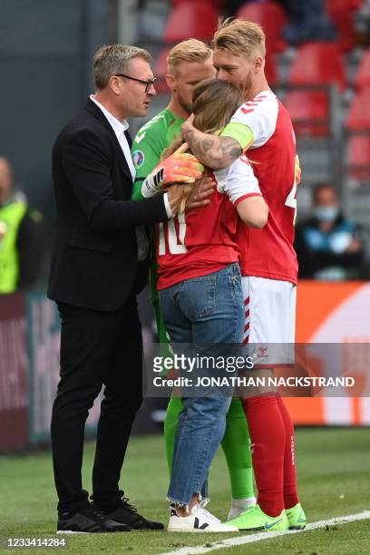 Sabrina Kvist Jensen , partner of Denmark's midfielder Christian Eriksen, is embraced by Denmark's defender Simon Kjaer as she reacts after Eriksen...