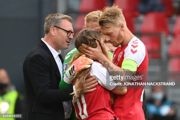 Sabrina Kvist Jensen , partner of Denmark's midfielder Christian Eriksen, is embraced by Denmark's defender Simon Kjaer as she reacts after Eriksen...