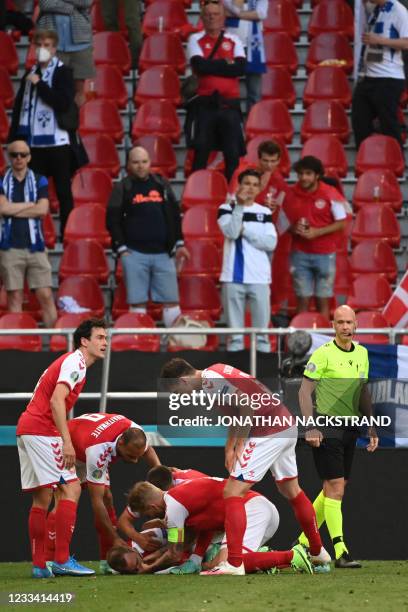 Denmark's players check on Denmark's midfielder Christian Eriksen during the UEFA EURO 2020 Group B football match between Denmark and Finland at the...