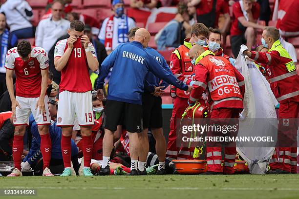 Denmark's players react as paramedics attend to Denmark's midfielder Christian Eriksen after he collapsed on the pitch during the UEFA EURO 2020...