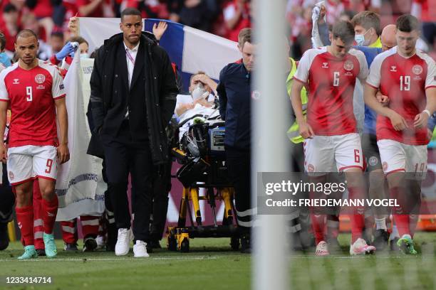 Denmark's players escort Denmark's midfielder Christian Eriksen as he is evacuated after collapsing on the pitch during the UEFA EURO 2020 Group B...