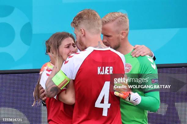 Denmark's goalkeeper Kasper Schmeichel and Denmark's defender Simon Kjaer comfort Sabrina Kvist Jensen, partner of Denmark's midfielder Christian...