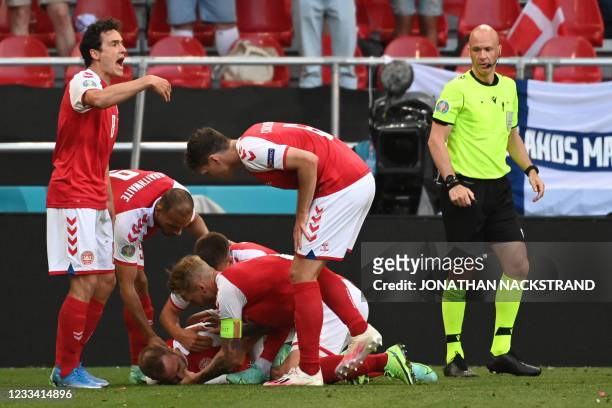 Denmark players help Denmark's midfielder Christian Eriksen after he collapsed during the UEFA EURO 2020 Group B football match between Denmark and...