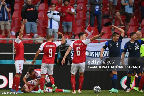 Denmark players help Denmark's midfielder Christian Eriksen as they call for medics after he collapsed during the UEFA EURO 2020 Group B football...