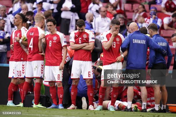 Denmark's players react as paramedics attend to Denmark's midfielder Christian Eriksen after he collapsed on the pitch during the UEFA EURO 2020...