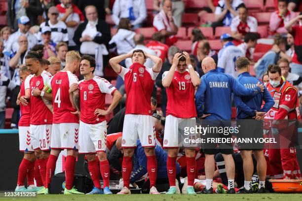 Denmark's players react as paramedics attend to Denmark's midfielder Christian Eriksen after he collapsed on the pitch during the UEFA EURO 2020...