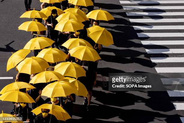 Protesters march through the street while holding yellow umbrellas during the demonstration. Pro-democracy demonstrators took to the streets in...