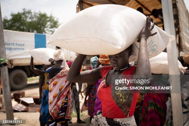 Women from Murle ethnic group carry bags of sorghum during a food distribution by United Nations World Food Programme in Gumuruk, South Sudan, on...