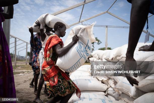 Women from Murle ethnic group carry bags of sorghum during a food distribution by United Nations World Food Programme in Gumuruk, South Sudan, on...
