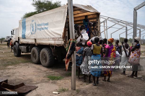 Women from Murle ethnic group unload bags of sorghum from a truck during a food distribution by United Nations World Food Programme in Gumuruk, South...