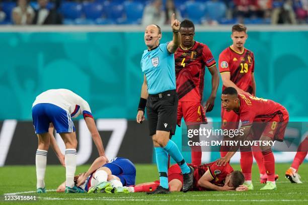 Spanish referee Antonio Miguel Mateu Lahoz gestures as Russia's midfielder Daler Kuzyaev and Belgium's defender Timoty Castagne lie on the ground...