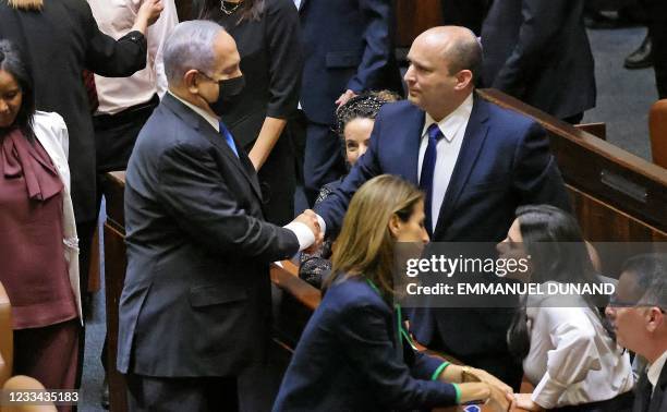 Israel's outgoing prime minister Benjamin Netanyahu shakes hands with his successor, incoming Prime Minister Naftali Bennett, after a special session...