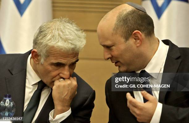 Israel's incoming Prime Minister Naftali Bennett and Alternate Prime Minister and Foreign Minister Yair Lapid converse together on during an address...