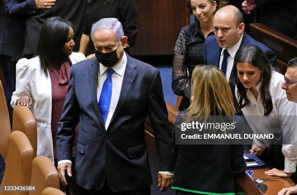 Israel's outgoing prime minister Benjamin Netanyahu walks past his successor, incoming Prime Minister Naftali Bennett , after a special session to...