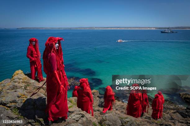 The Red Rebel Brigade which is part of the Extinction Rebellion movement pose on St Ives Head. Environmental Protest Groups gather in Cornwall as the...