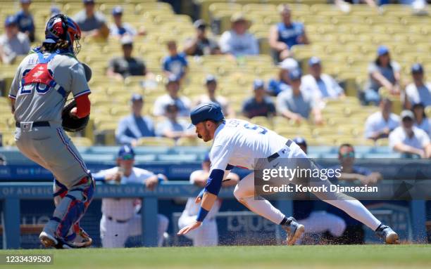 Gavin Lux of the Los Angeles Dodgers is caught in a rundown between third base and home plate and tagged out by catcher Jonah Heim of the Texas...