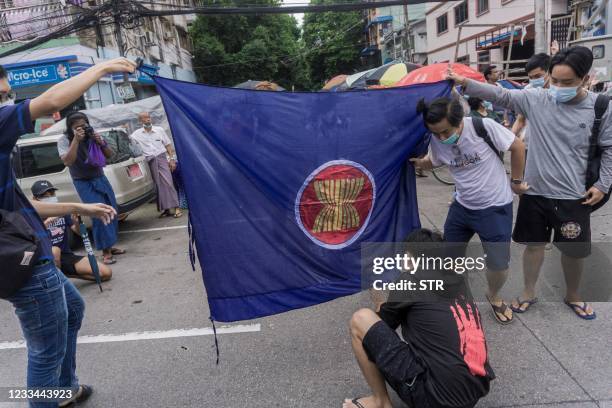 Protesters prepare to burn the flag of the Association of Southeast Asian Nations grouping, as they take part in a flash mob demonstration against...