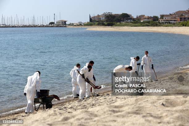 Firemen and civil security members clean the beach of Scaffa Rossa in Solaro on June 14 after a boat polluted the sea on June 11, off the coast of...