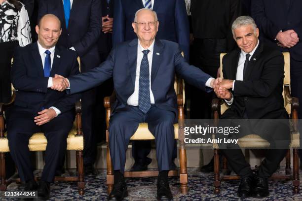 Israeli President Reuven Rivlin sits next to Israeli Prime Minster Naftali Bennett and Foreign Minister Yair Lapid as they pose for a group photo...