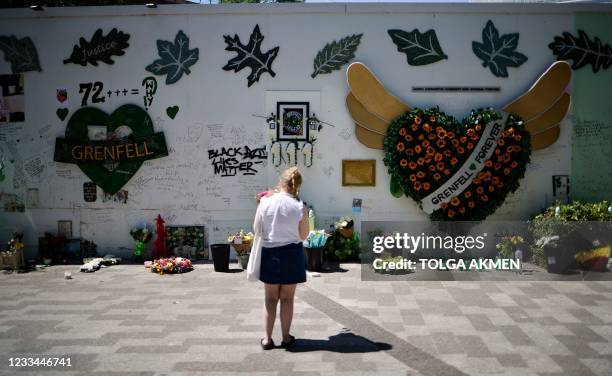 Woman holds a bouquet of flowers as she looks at a memorial to the victims of the Grenfell Tower fire, in west London on June 14 four years after the...