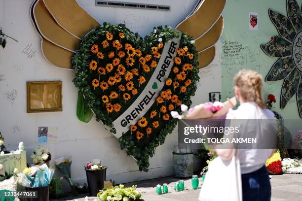 Woman holds a bouquet of flowers as she looks at a memorial to the victims of the Grenfell Tower fire, in west London on June 14 four years after the...