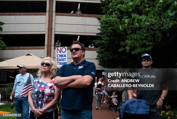 People listen to speakers during a rally against "critical race theory" being taught in schools at the Loudoun County Government center in Leesburg,...