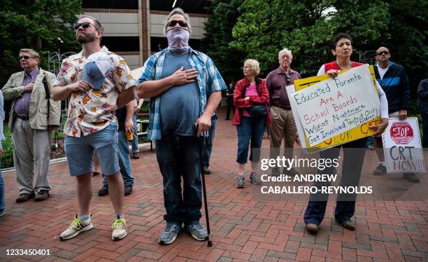 People hold up signs during a rally against "critical race theory" being taught in schools at the Loudoun County Government center in Leesburg,...