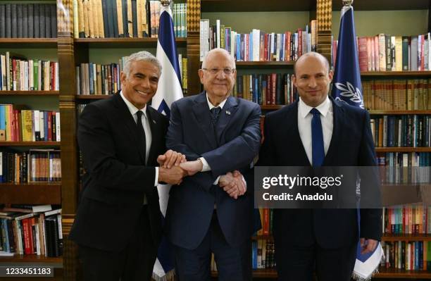 Israeli President Reuven Rivlin shake hands with Prime Minister Naftali Bennett and Alternate Israeli Prime Minister and Foreign Minister Yair Lapid...