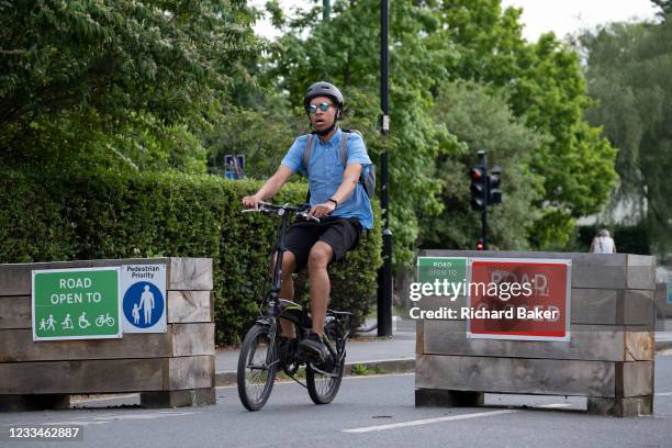 Cyclist passes through the barriers that form an LTN , an experimental closure by Southwark Council preventing motorists from accessing the junction...