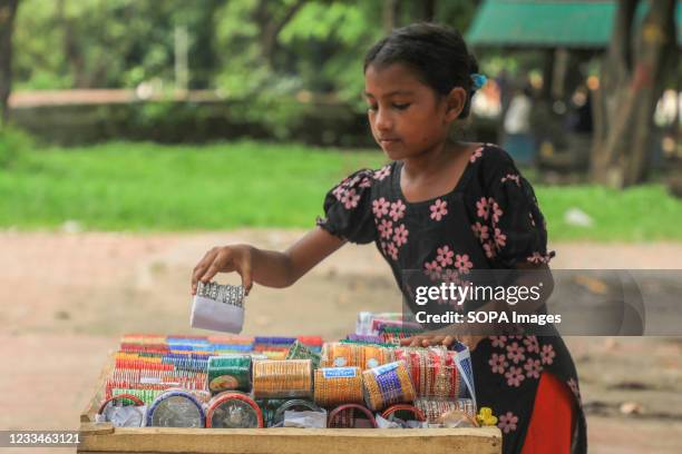 Bangladeshi street child vendor Fahima Akter, arranges bangles at a road side market.