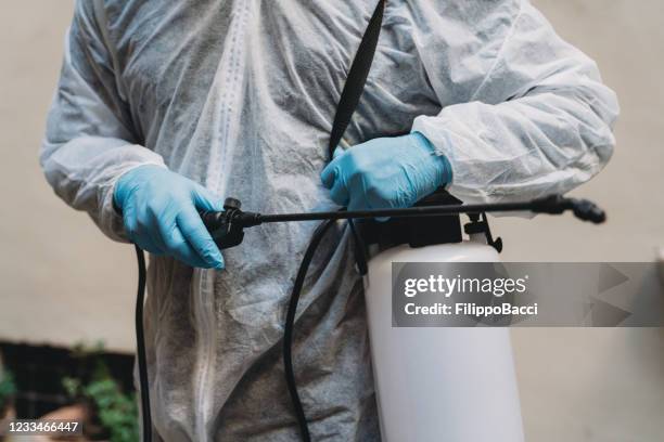 detail of a sanitation worker in protective suit holding a sprayer - crop sprayer imagens e fotografias de stock