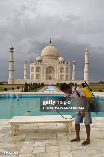 Sanitation worker sprays disinfectant on the marble bench at the premises of Taj Mahal mausoleum on the eve of its reopening to public after two...