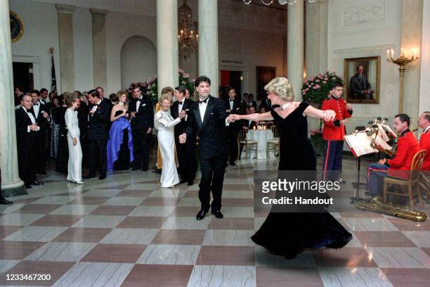 In this handout image provided by The White House, Princess Diana dances with John Travolta in Cross Hall at the White House during an official...