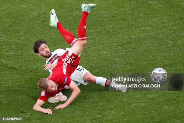 Hungary's midfielder Andras Schafer falls over Portugal's midfielder Bernardo Silva during the UEFA EURO 2020 Group F football match between Hungary...