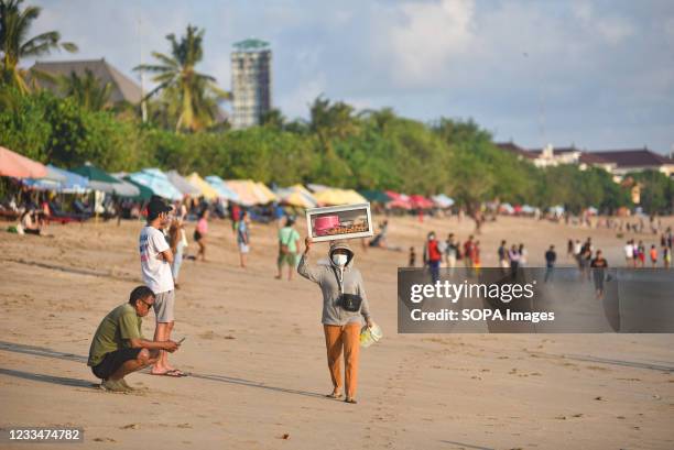 Beach vendor carries her goods on her head at the beach. Bali as one of the world tourism destination closed its international tourism since Covid-19...