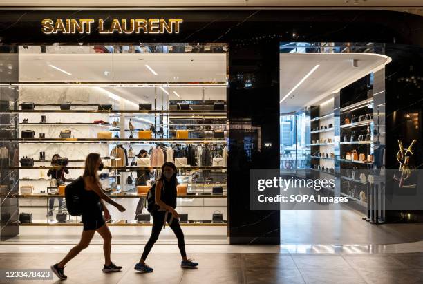 Shoppers walk past the French luxury fashion brand Yves Saint Laurent store seen in Hong Kong.