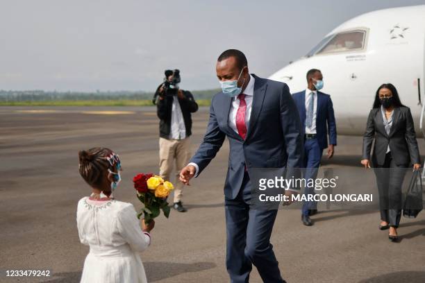 Ethiopian Prime Minister Abiy Ahmed is offered a bouquet of flowers by a child as he disembarks the plane upon his arrival in Jimma on June 16, 2021...