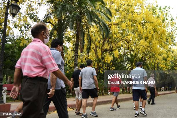 People take their daily exercise walking under Amaltas trees in a public garden in Amritsar on June 16, 2021.